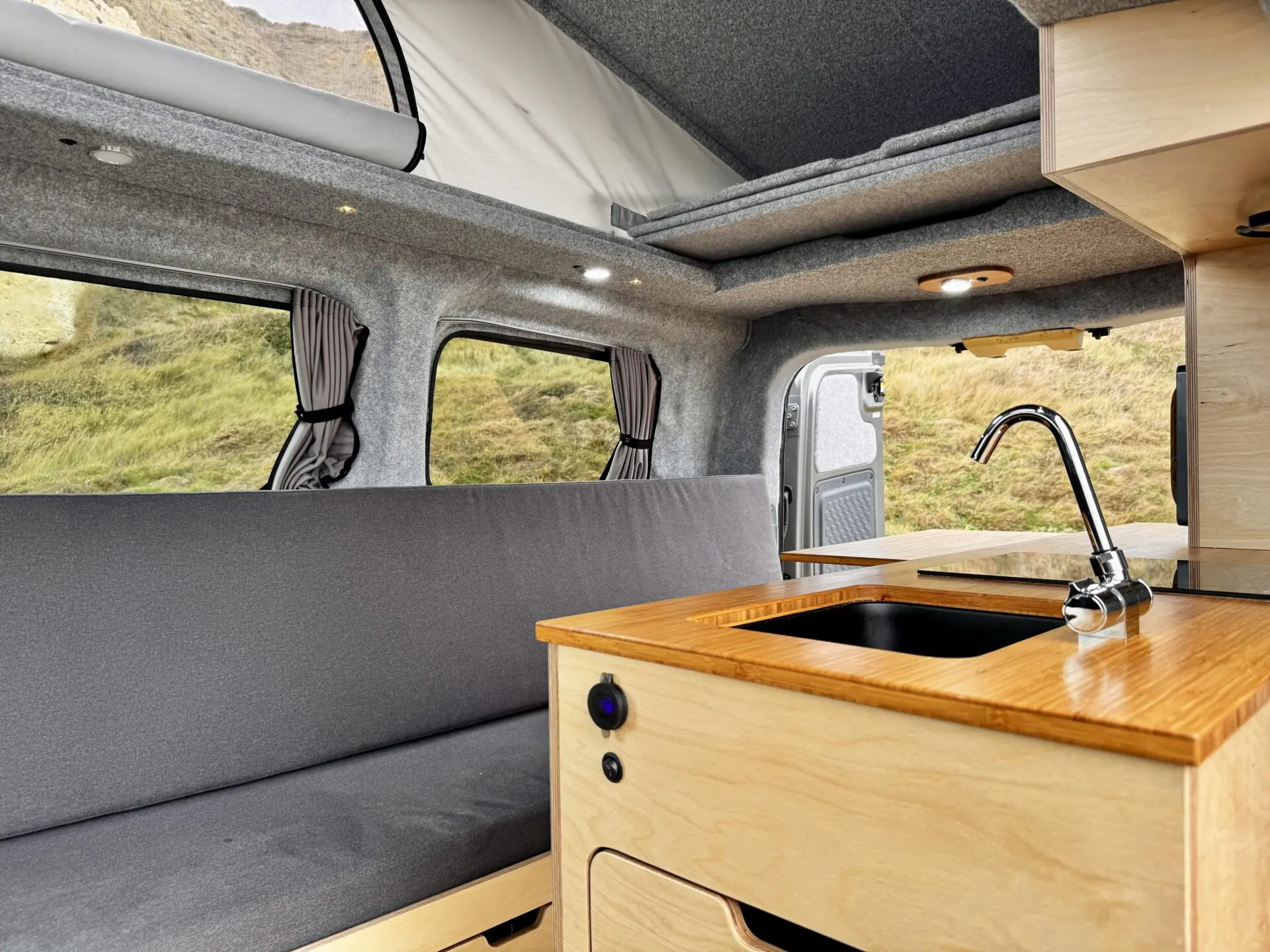 Kia PV5 campervan kitchen with sink and grey bench seat