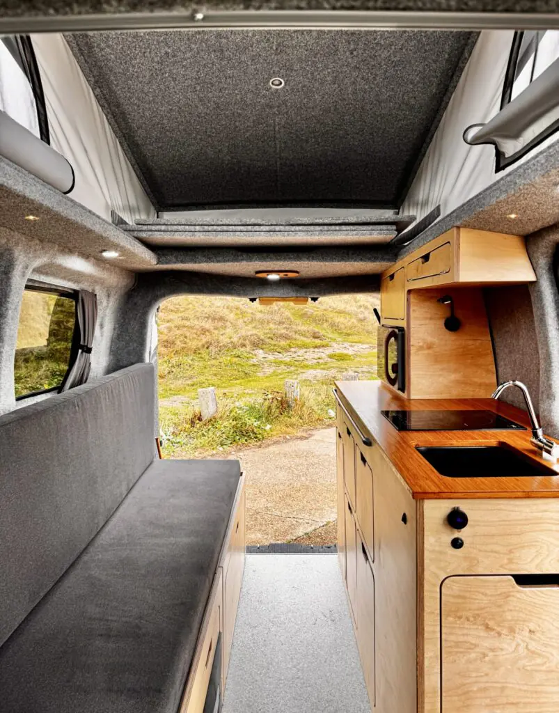 Kia PV5 campervan interior with grey seats and wooden kitchen